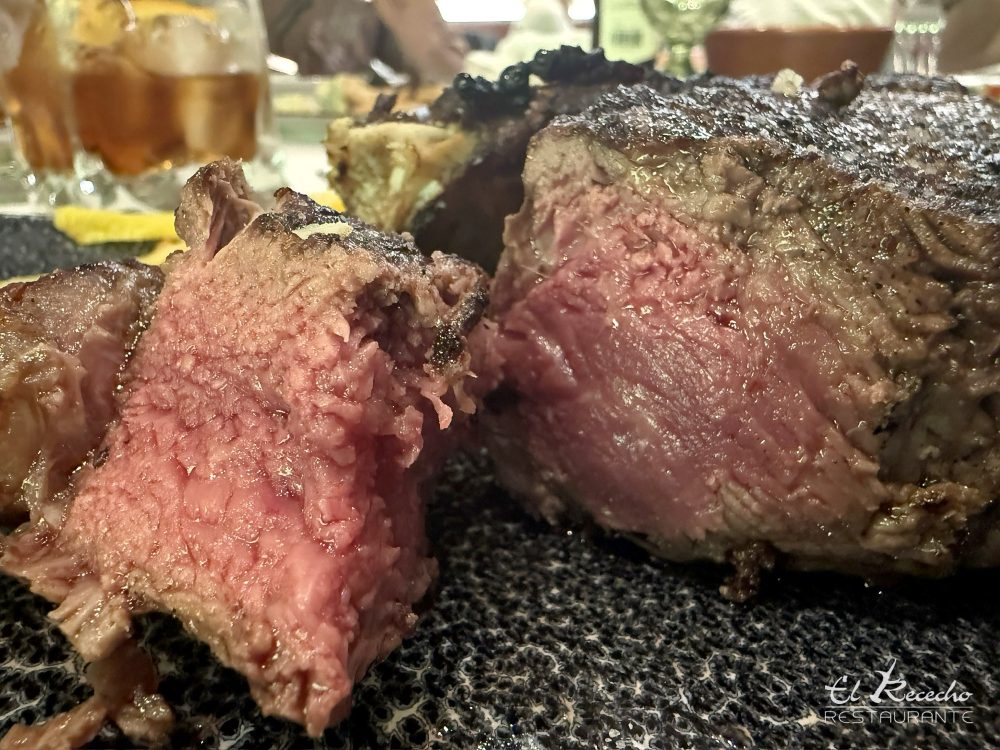 Chuletón madurado cortado que muestra el punto rosado y jugoso del interior