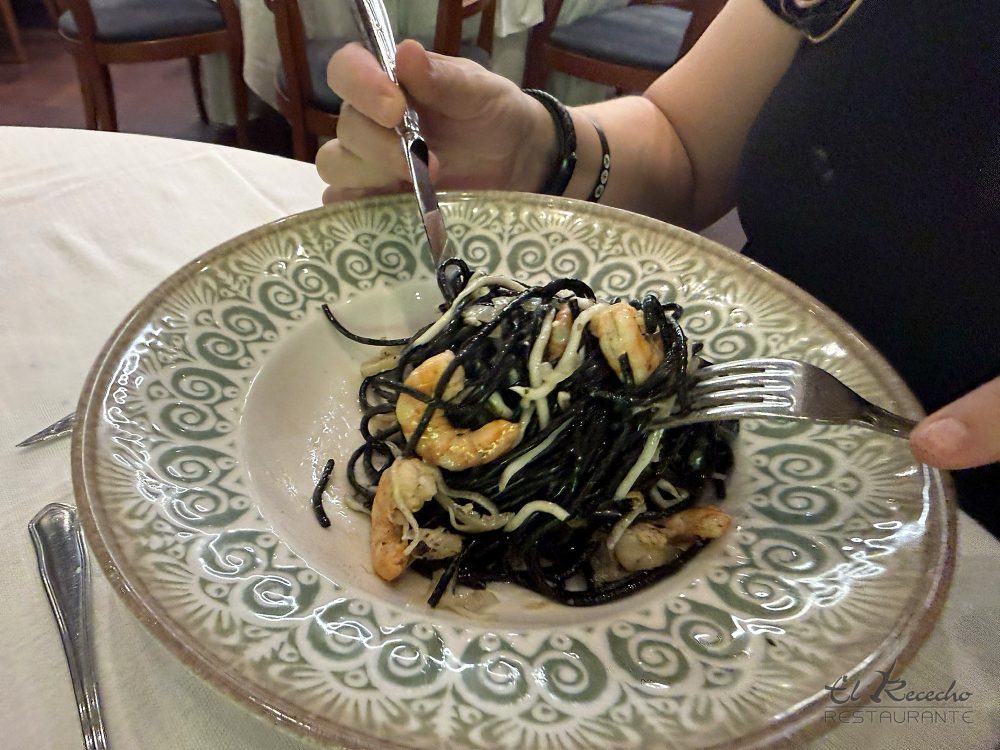 Plato de espaguetis negros con gambas en plato de cerámica verde